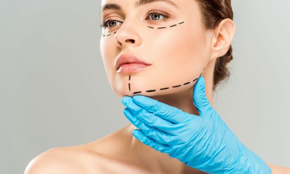 Cropped,View,Of,Plastic,Surgeon,Touching,Face,Of,Attractive,Woman